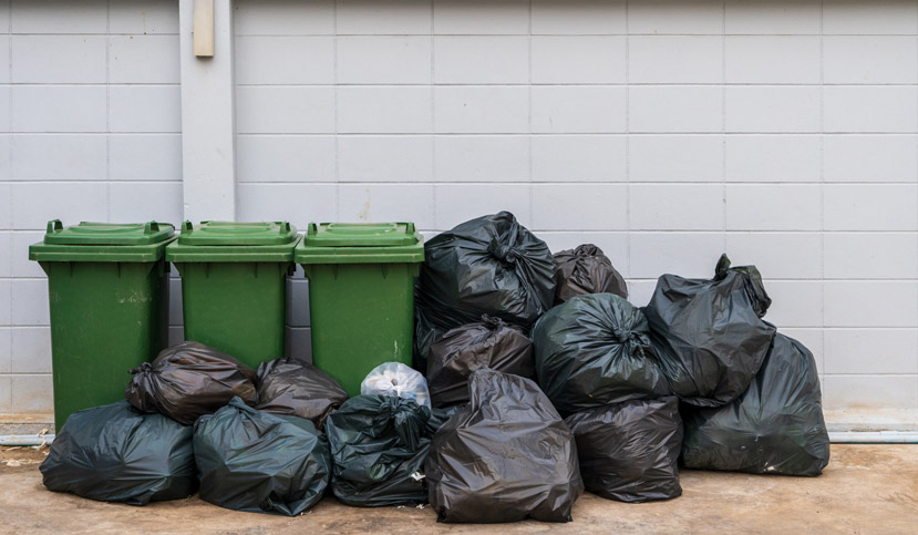 Garbage in black bags is placed with garbage bins to be separated into the waste management system.