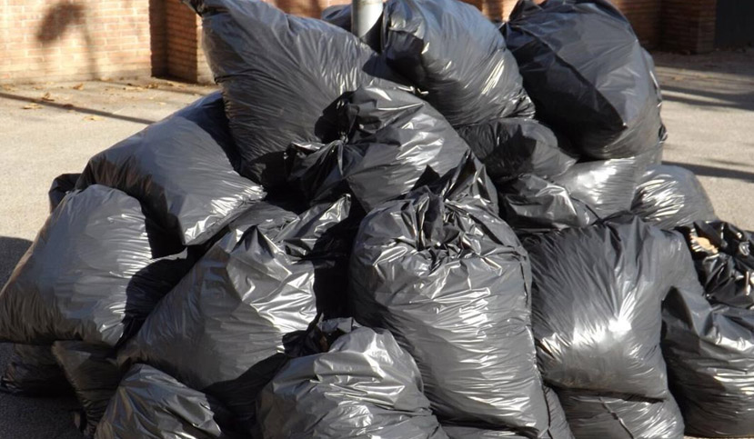 Garbage in black bags is placed with garbage bins to be separate